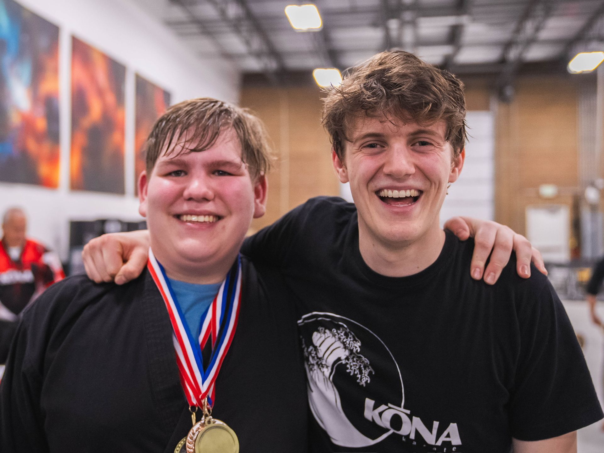 A Kona Karate student wearing medals with his coach